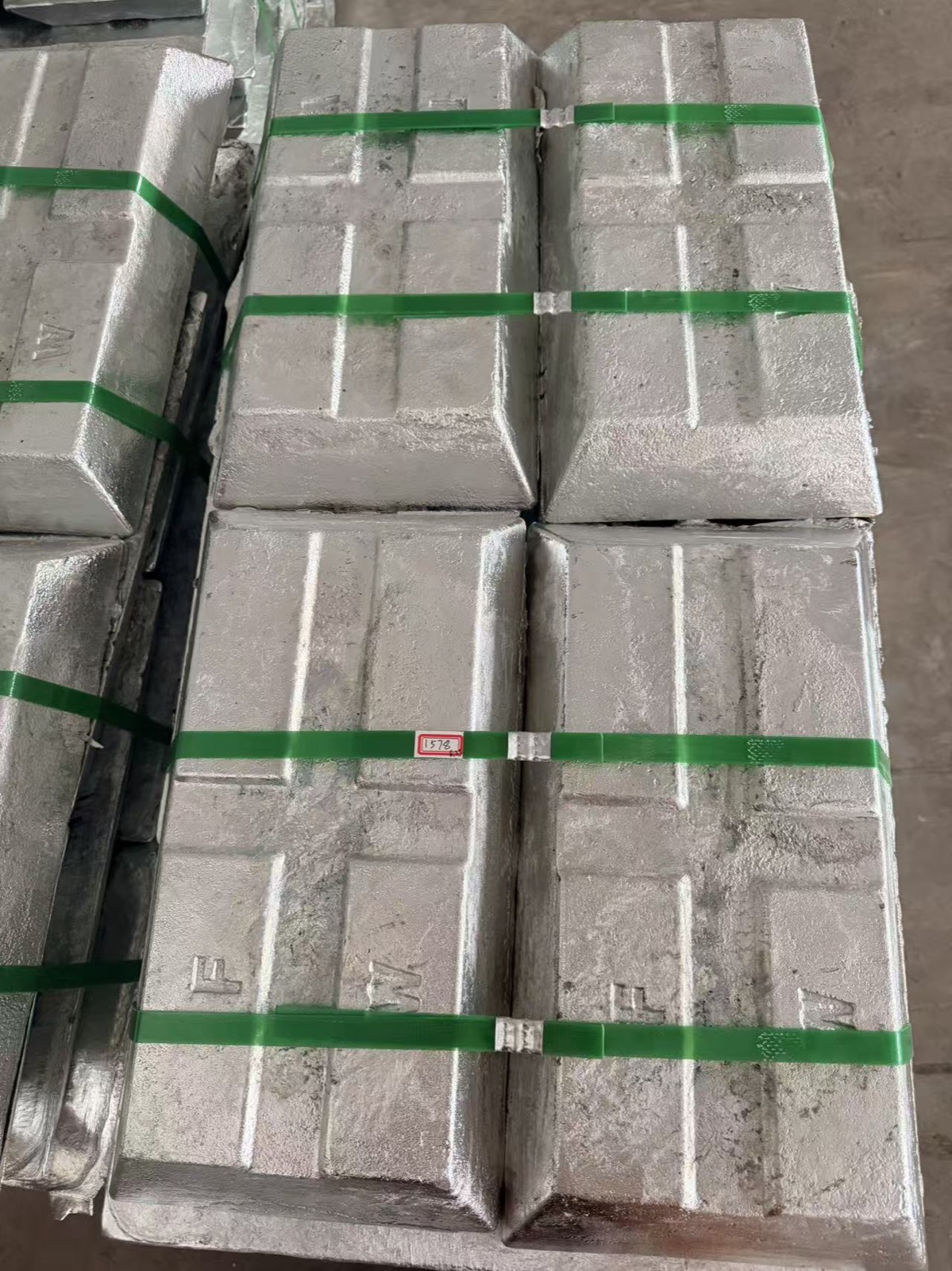 绿色打包带捆扎的银灰色金属锭表面细节